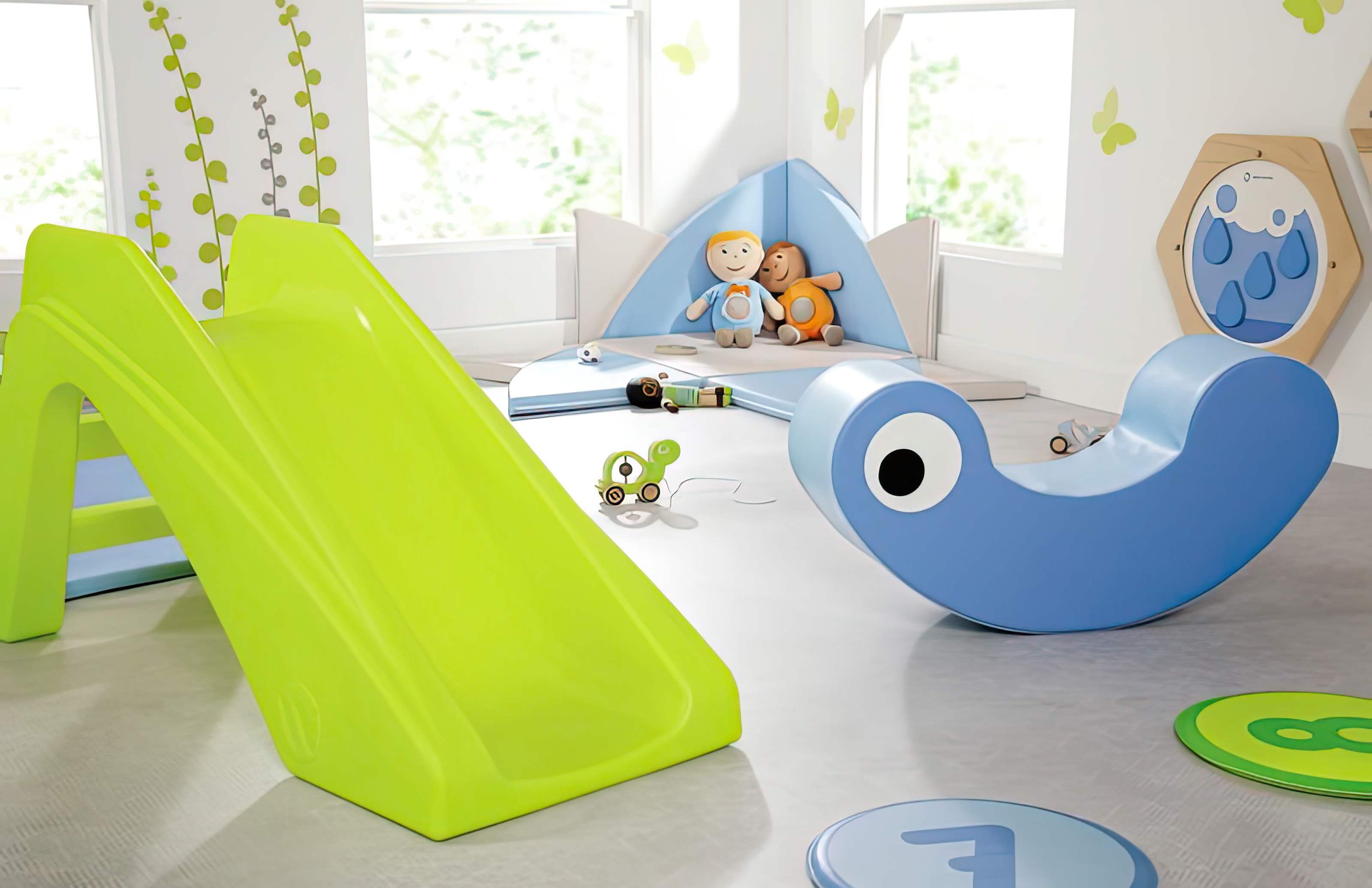 Ein Kinder Spielbereich mit einer Rutsche, Wippe, Sitzkissen und weiteren Spielelementen