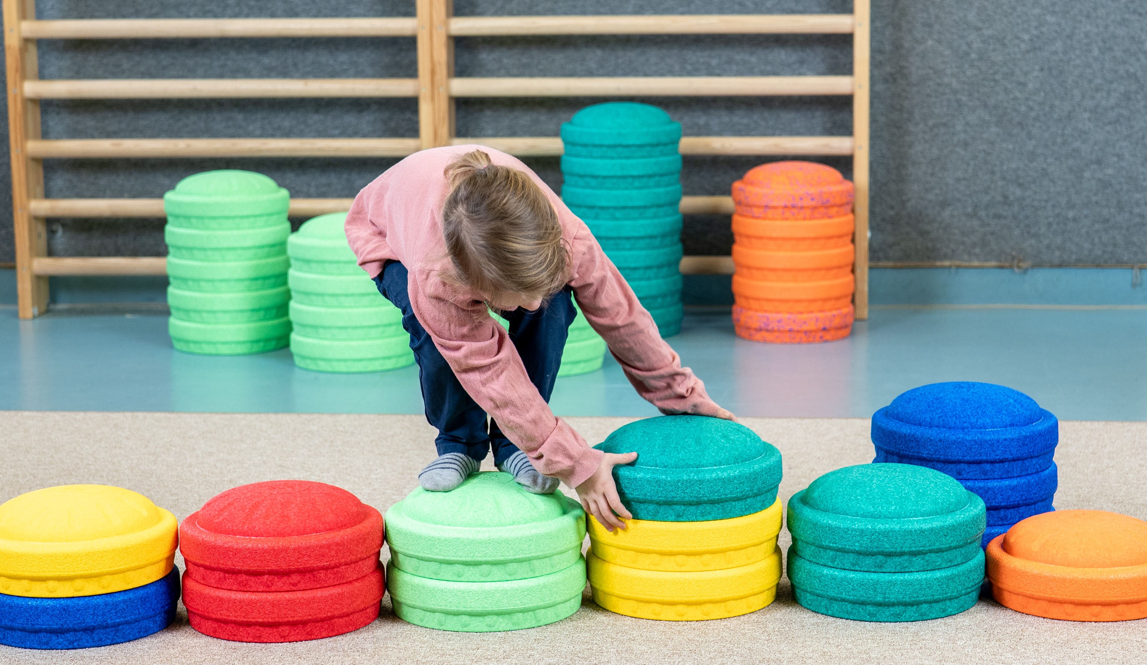 Ein Kind spielt in einer Turnhalle mit den Spielbausteinen "MyFunStone" von Besonderes4Kids