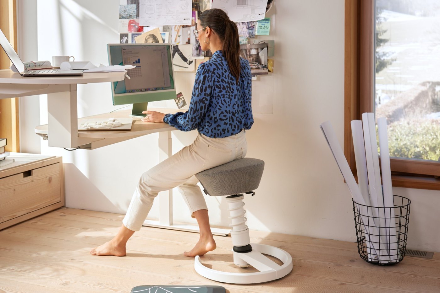 Frau arbeitet am Schreibtisch auf einem weißen Aeris Swopper