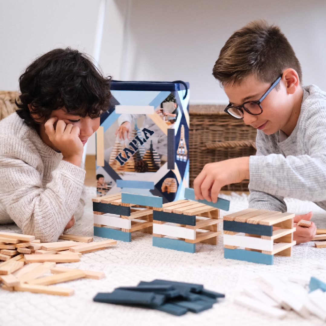 LP Kapla Holzspiel Auf dem Bild sind zwei Kinder mit Holzplättchen am spielen.