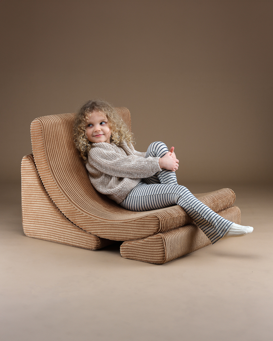 Ein Mädchen sitzt auf dem Kindersessel "Moon-Chair" von Wigiwama