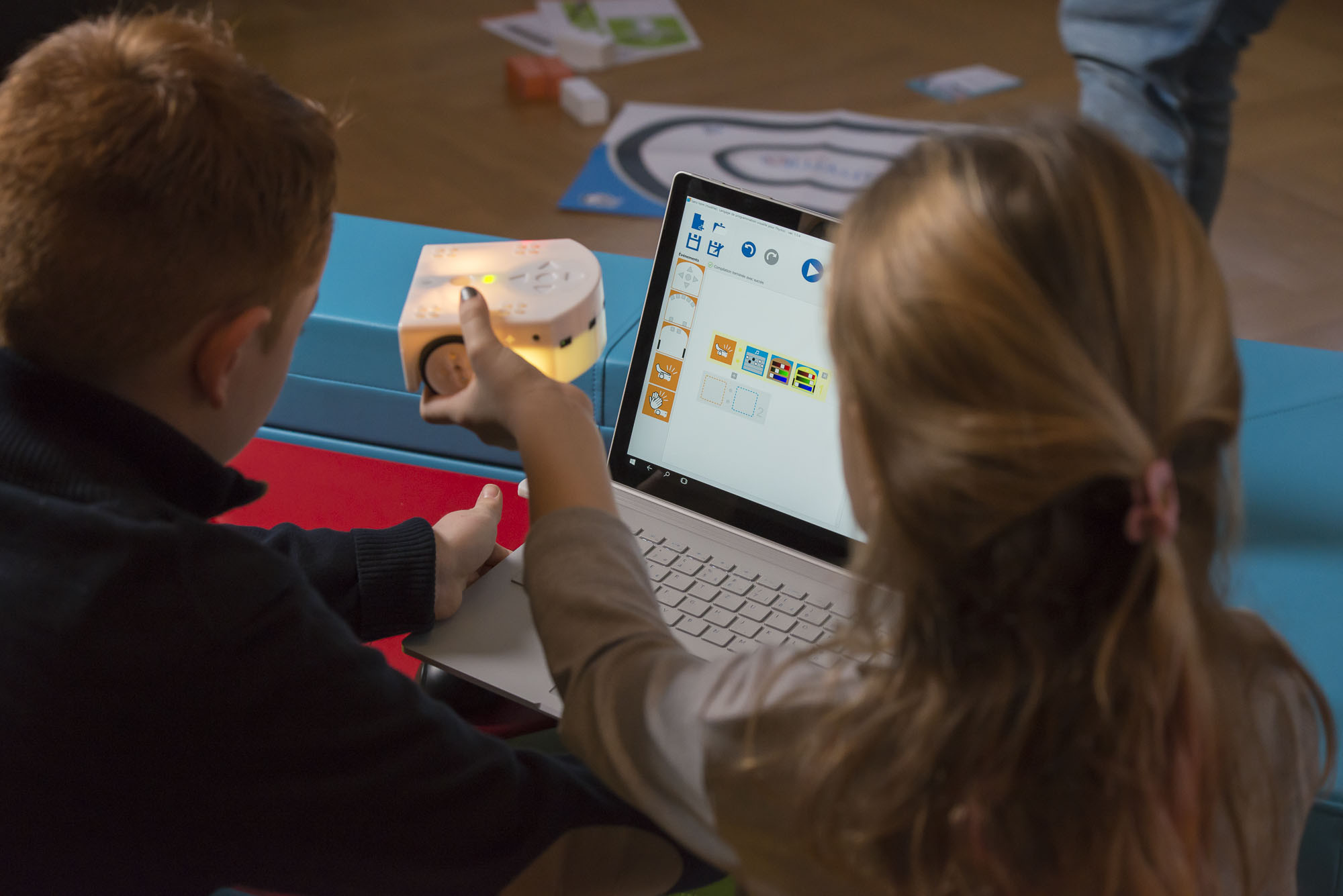 Thymio Lernroboter Unterricht Zwei Kinder sitzen mit dem Thymio Lernroboter vor einem Laptop und programmieren diesen.