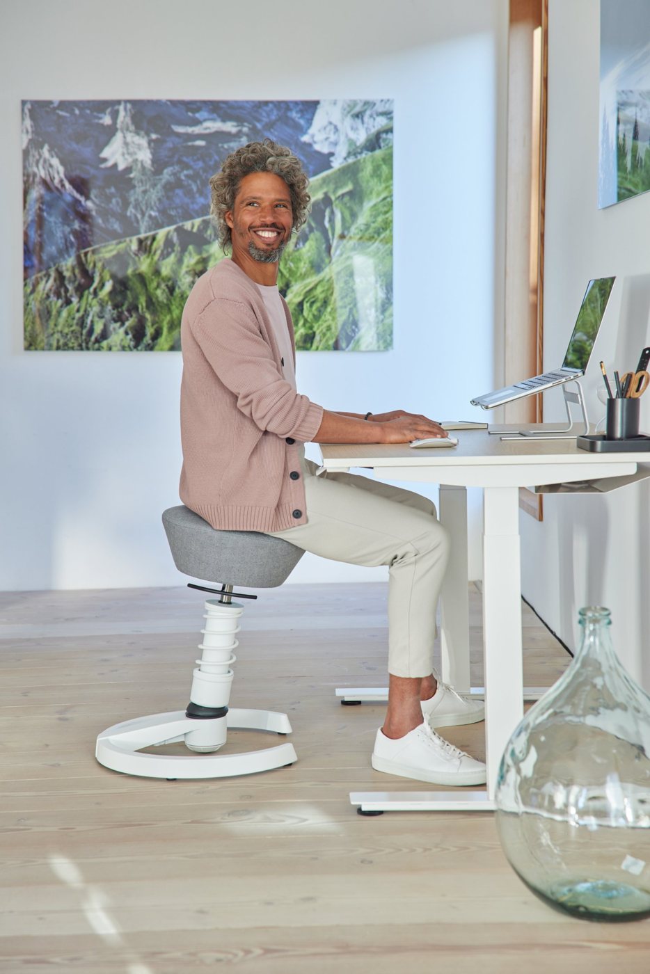 Mann arbeitet auf einem weißen Aeris Swopper am Schreibtisch