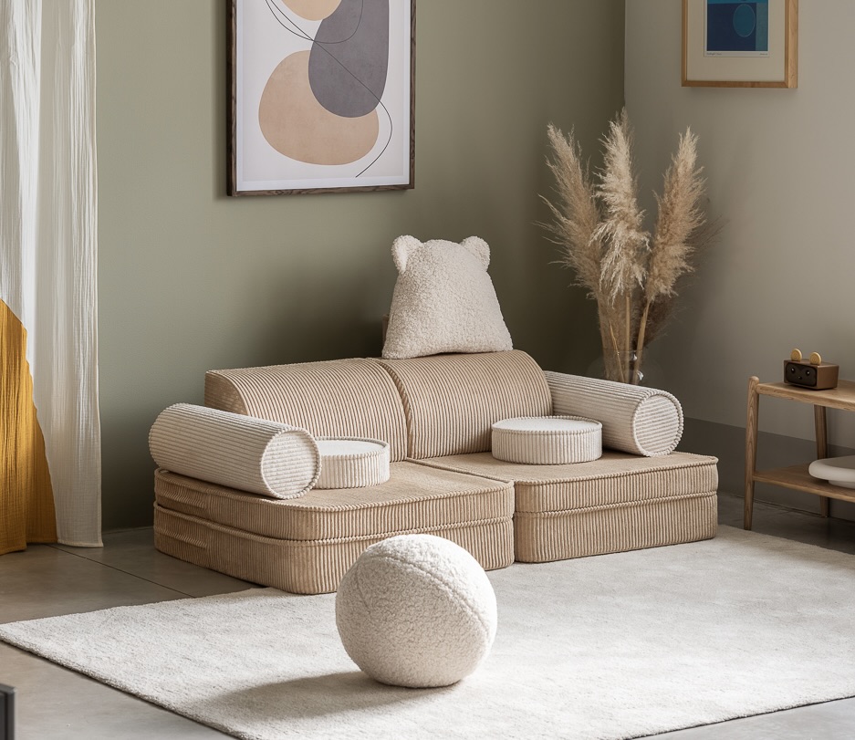 Auf dem Bild ist ein beiges Kindersofa, mit Dekoration und Kissen